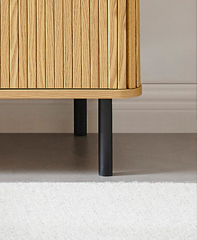 Slim, black cyclindrical metal legs support the chest atop a light-toned floor. Slim, black cyclindrical metal legs support the chest atop a light-toned floor.