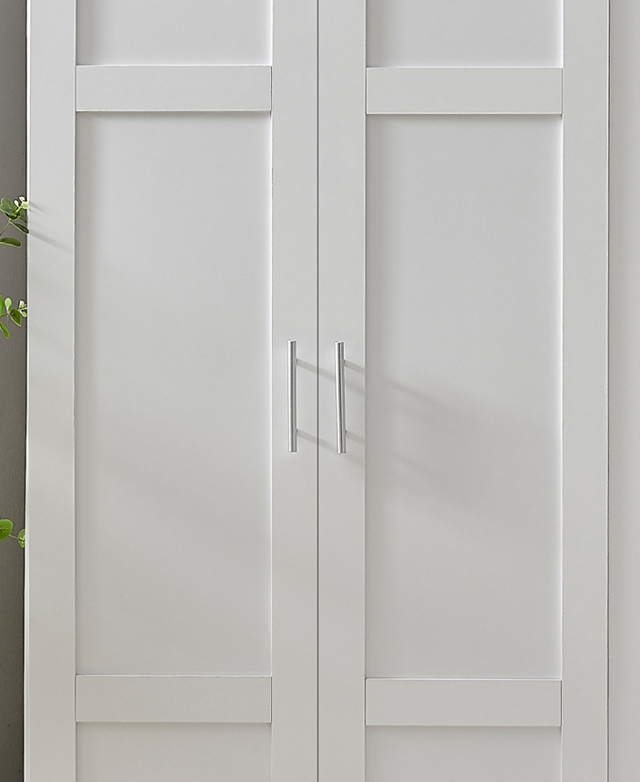 Shaker-style cupboard doors of the white cupboard are in focus, with sleek silver bar handles shown.