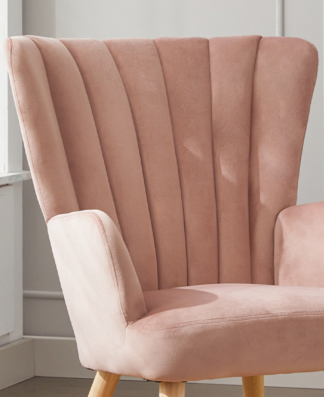The fan-shape of the pink armchair is complete with neat channel stitching. The wingback shape is a mid-height backrest. The fan-shape of the pink armchair is complete with neat channel stitching. The wingback shape is a mid-height backrest.