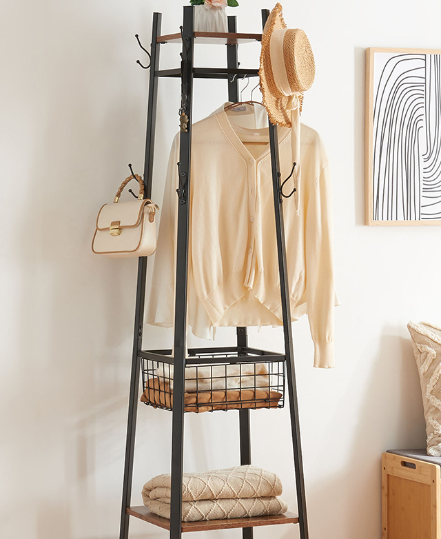 The coat rack is filled with hanging clothing, a hat, a bag, and blankets in a warm, bright room. The coat rack is filled with hanging clothing, a hat, a bag, and blankets in a warm, bright room.