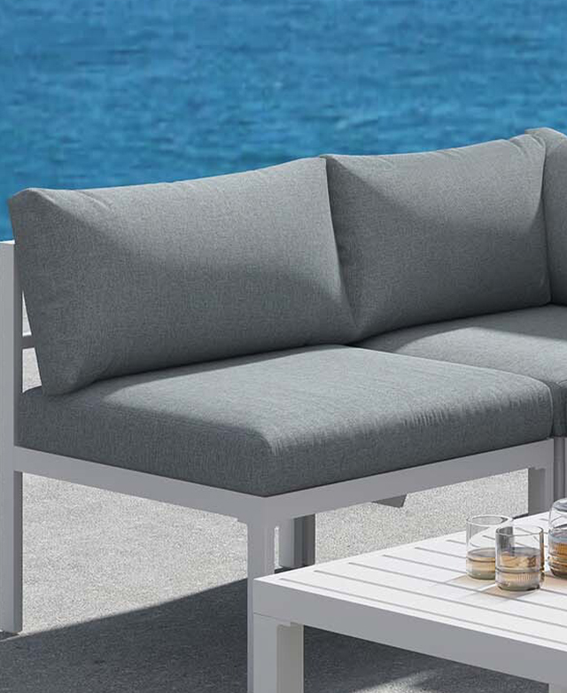 A portion of the grey and white outdoor sofa is shown outside with a pool in the background.