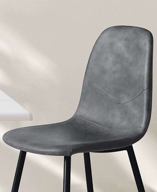 The rounded edges of the grey seat are emphasised by smooth faux leather upholstery. A seam sweeps across the backrest.