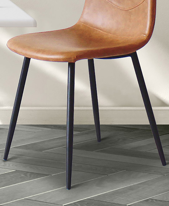 The four tapered black metal legs of the tan dining chair are in the frame, on grey parquet-style tiles.