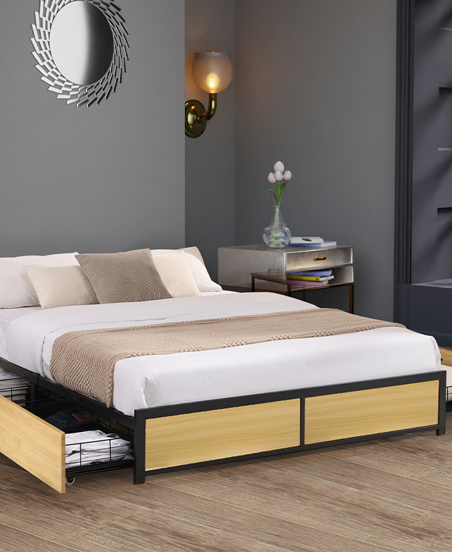 The bed is dressed in neutral tones in a grey bedroom. A side table with a bouquet of pink tulips is next to it.