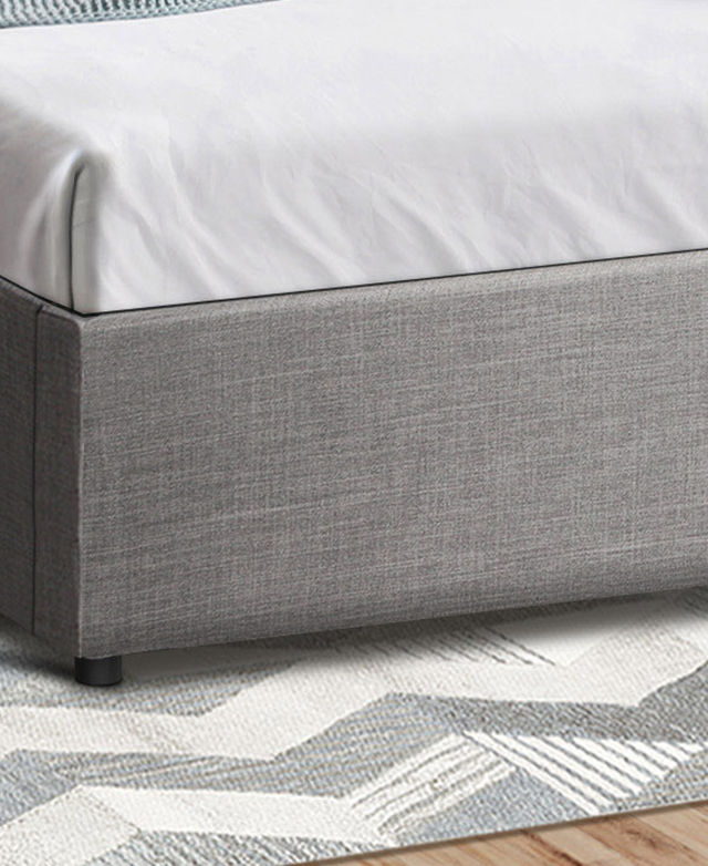A close-up shot of the bed base shows its linen-like texture. It's on a geometric monochrome rug. A close-up shot of the bed base shows its linen-like texture. It's on a geometric monochrome rug.