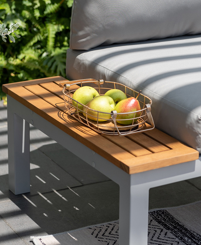 The seat's eucalyptus-top side table has a bowl of fruit on top.