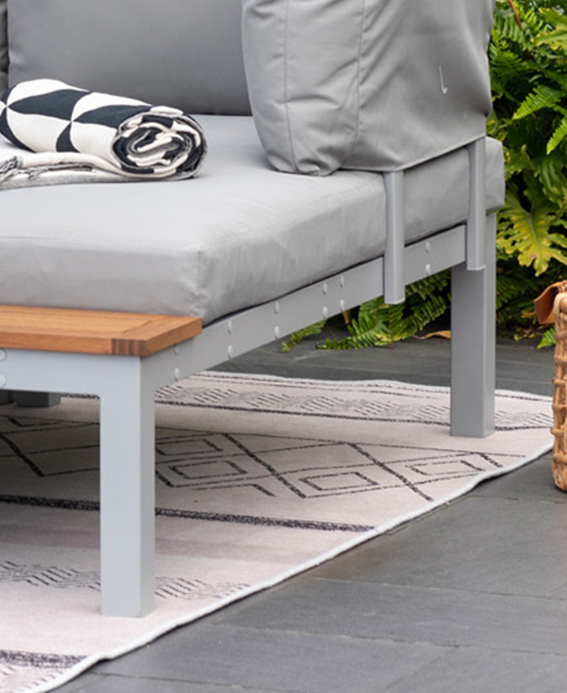 The grey metal frame of an outdoor lounge is in focus; it's on a monochrome patterned rug.