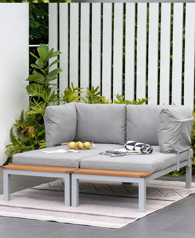 Two lounges are pushed together to form an oblong-shaped seat. A blanket, basket of fruit, and magazine are on top.