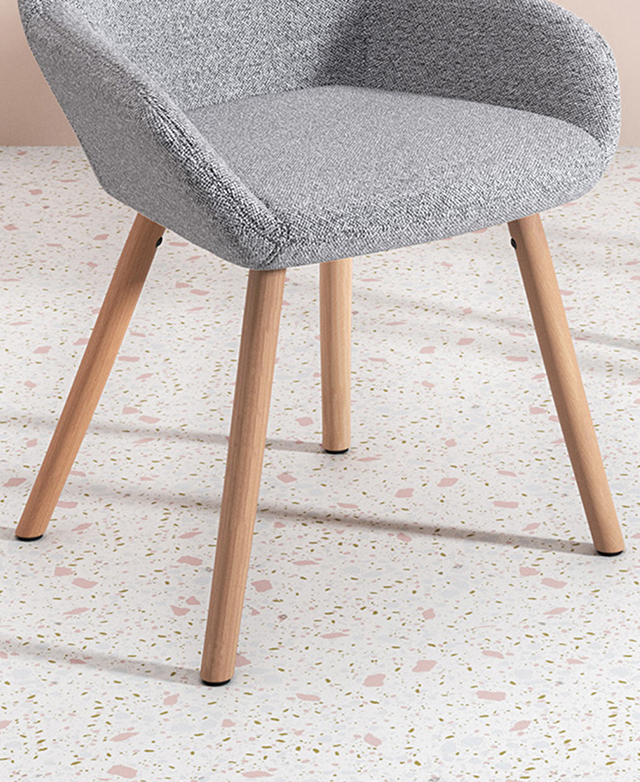 The splayed beech wood legs, which include black foot protectors, are on a pink-toned terrazzo floor.
