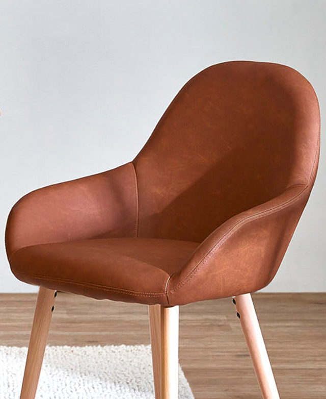 The tan dining chair's seat is shown at an angle to showcase the smooth sloping arms and the rounded features.