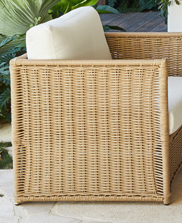 A side view of an outdoor armchair displays the woven polyethylene rattan frame.