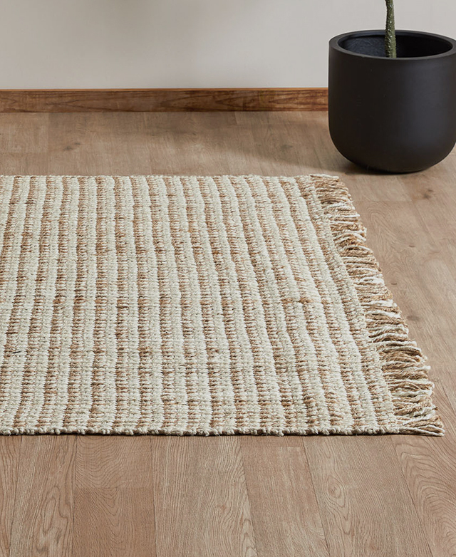 The reversible jute rug is lain flat on a timber floor with a black plant pot next to it. The reversible jute rug is lain flat on a timber floor with a black plant pot next to it.
