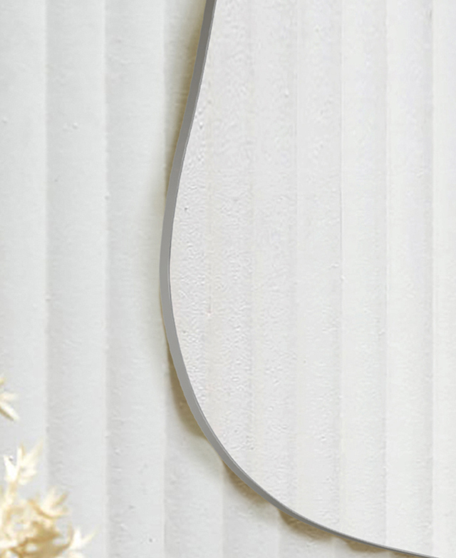Cropped view highlights the curved, smooth edge of the mirror on a white, fluted wall. Cropped view highlights the curved, smooth edge of the mirror on a white, fluted wall.