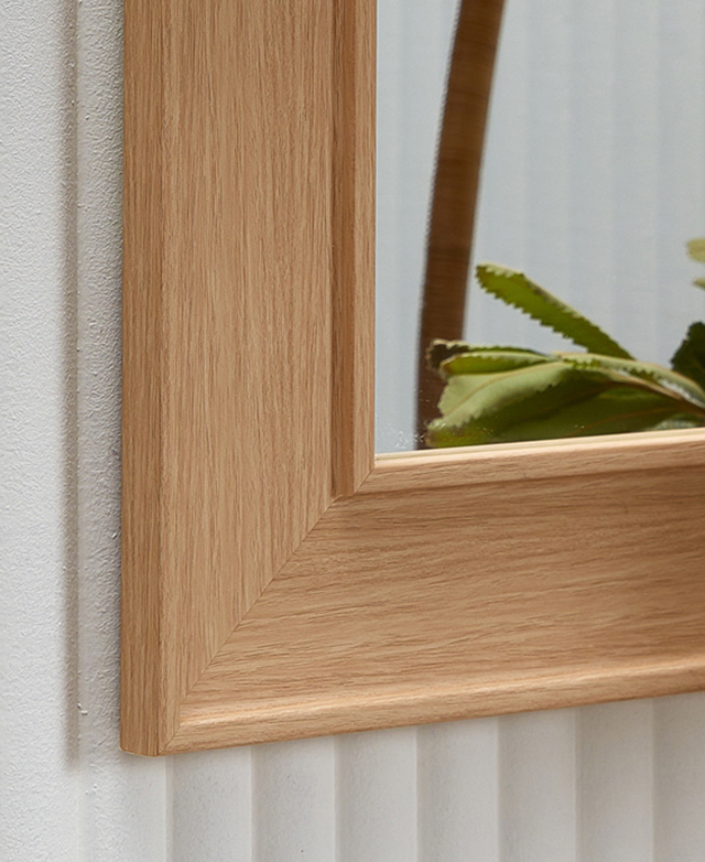 Recessed mirror frame has oak tones with the appearance of uniform grains, shown against a white fluted wall. Recessed mirror frame has oak tones with the appearance of uniform grains, shown against a white fluted wall.