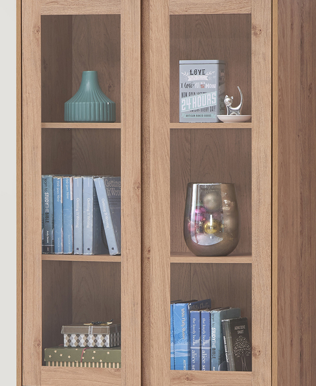 Two cupboard doors have central clear glass panels, which show decorative items and books on the enclosed shelves. Two cupboard doors have central clear glass panels, which show decorative items and books on the enclosed shelves.