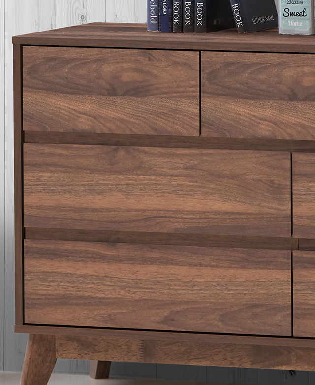 The clean lines of the walnut chest of drawers are shown close up. Books are on top. The clean lines of the walnut chest of drawers are shown close up. Books are on top.