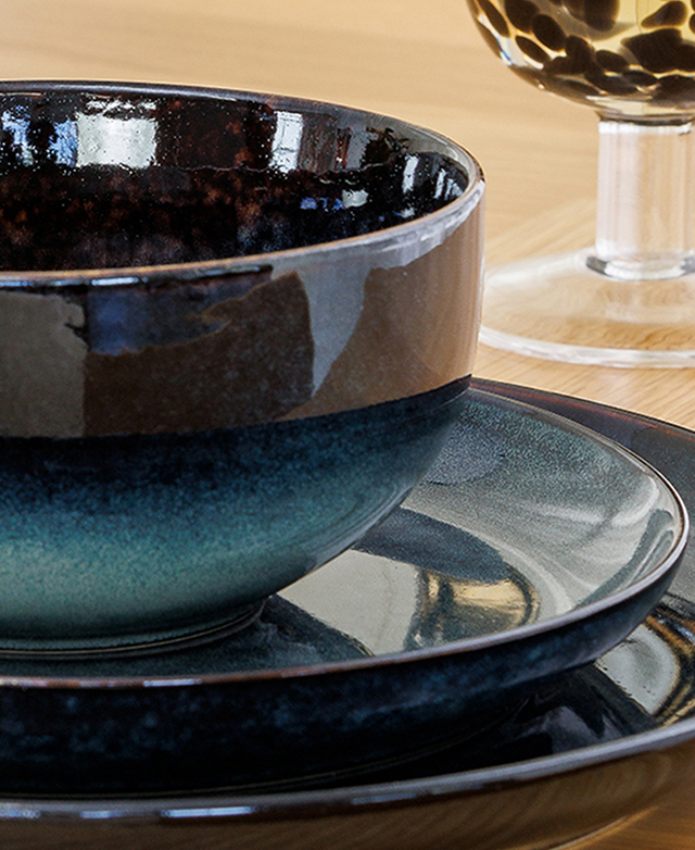 A close view of a blue bowl, side plate, and dinner plate emphasises the glossy finish of the ceramic.