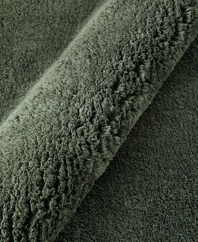 The green rug is folded back on itself to magnify its thick pile.