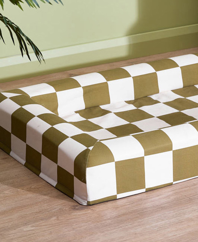 The khaki and white checkered walled dog bed is on a timber floor.