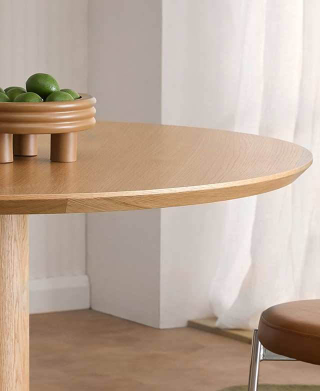 Cropped view highlights the neat bevelled edge of the round table; a bowl of limes is on top.
