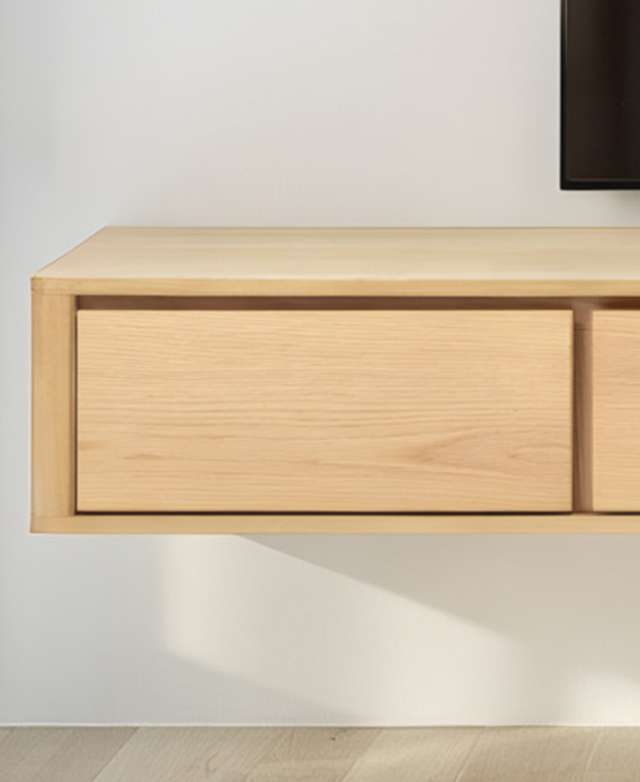 Cropped view of the end of the TV unit is affixed to a white wall; the streamlined shape and handle-free design is in focus. Cropped view of the end of the TV unit is affixed to a white wall; the streamlined shape and handle-free design is in focus.
