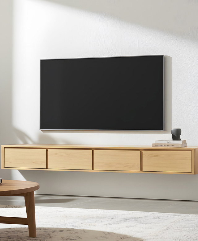 The long oak TV unit is fixed to a white wall in a bright room, with a TV attached to the wall above it. The long oak TV unit is fixed to a white wall in a bright room, with a TV attached to the wall above it.