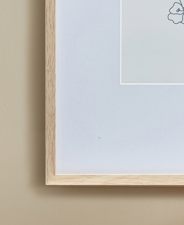 Cropped view draws attention to the bottom corner of the wood-look frame and the deep mat within.