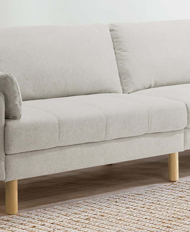 The seat is the focus of the neutral sofa, which has broad channel stitching and generously filled cushions.