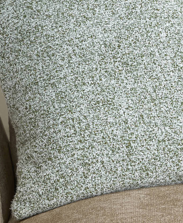 Two-tone green boucle fabric of a cushion is shown up close.