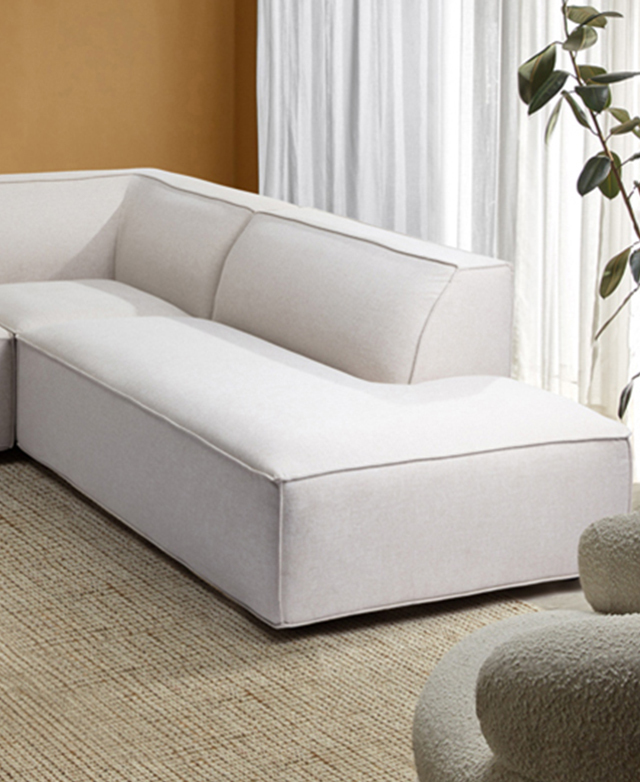 The cream sofa is in a yellow room, on top of a taupe rug; the seat is chunky, with tailored trims.
