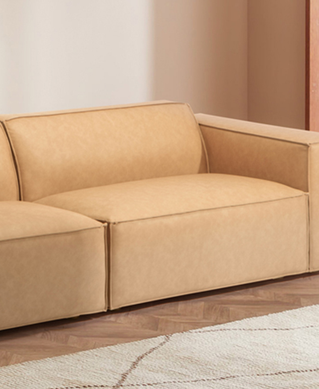 The chunky tan sofa is shown on rich parquet wood flooring in a bright room. The chunky tan sofa is shown on rich parquet wood flooring in a bright room.