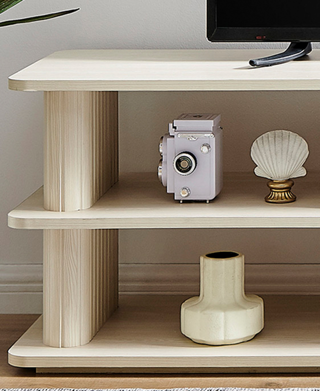 Cropped view shows one end of the cream TV unit filled with decor and topped with a TV.