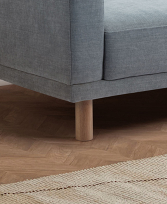 Cropped view shows a corner of the sofa next to a cream rug.