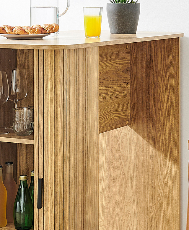 An oblique angle highlights the rounded corners of the bar table and its built-in storage. Breakfast is laid out on top.