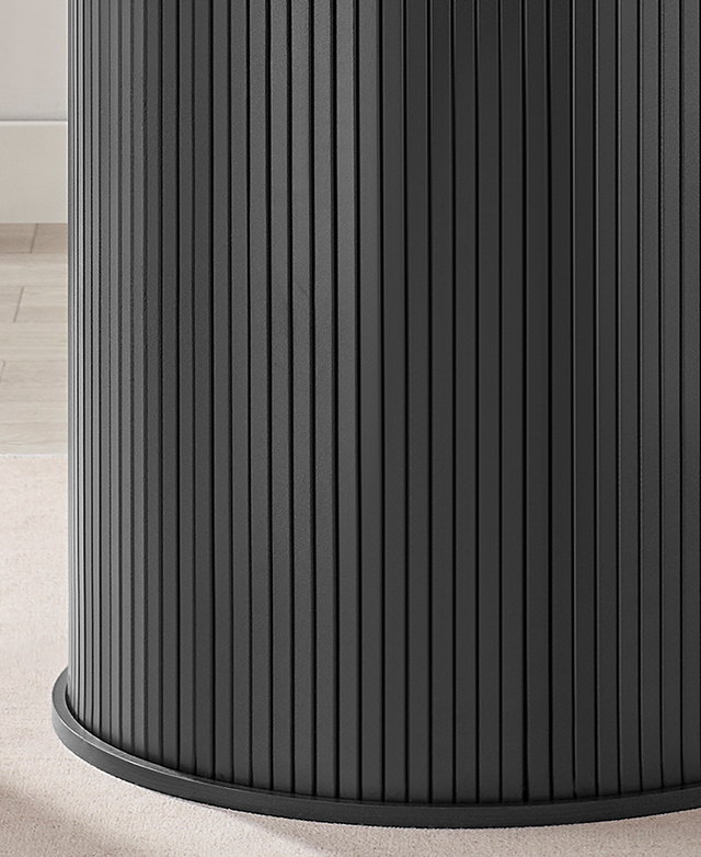 The thick black pedestal base of the dining table has a fluted exterior. The thick black pedestal base of the dining table has a fluted exterior.