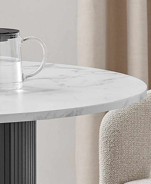 Close view of the round dining table emphasizes the marble effect top; it has a glass jug on top. Close view of the round dining table emphasizes the marble effect top; it has a glass jug on top.