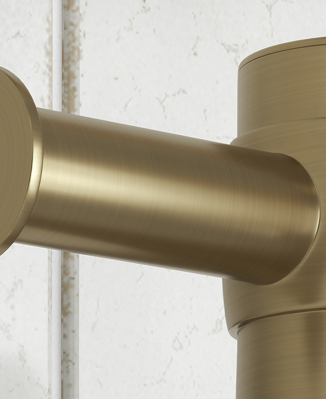 Gold towel rail junction close-up with satin finish on white tiled wall.