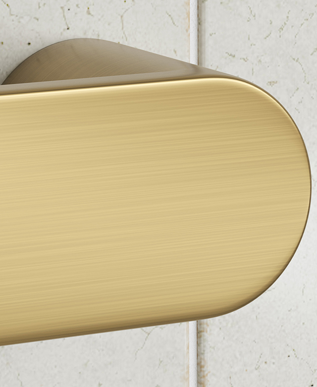 Gold oval-profile towel rail end cap on white tiled wall.