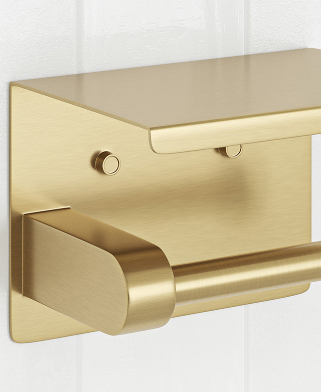 Brushed gold toilet roll holder with shelf, wall-mounted on white tiles.