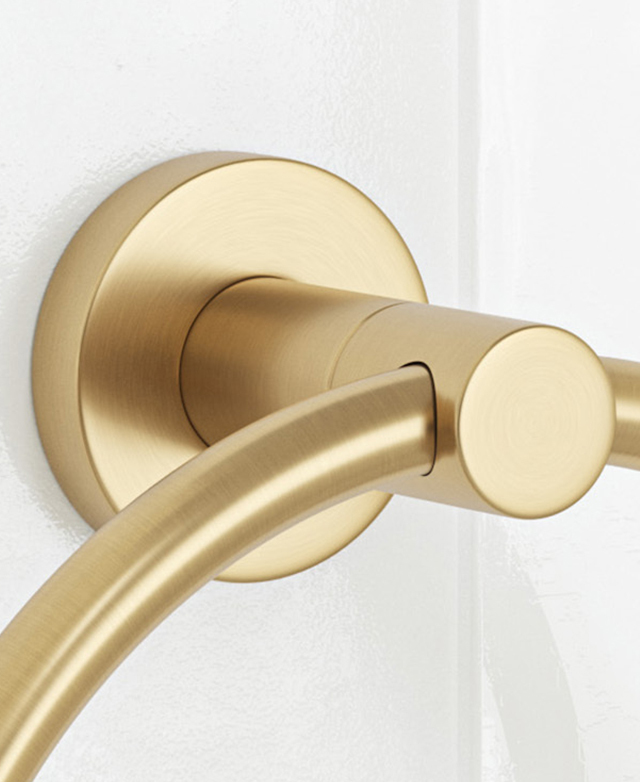 Brushed gold curved towel rail bracket close-up on glossy white tiles.